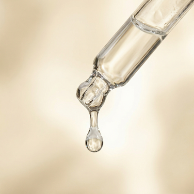 Hands holding Velvetics Hydra Depth Serum glass dropper bottle